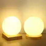 Modern table lamp with iron body and wood base illuminating a cozy bedroom