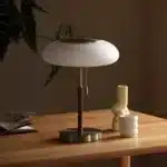 White glass table lamp with vintage design on a wooden desk in a cozy bedroom