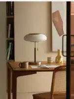 White glass table lamp with vintage design on a wooden desk in a cozy bedroom