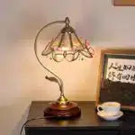 Vintage desk lamp with stained glass butterfly shade casting warm glow on bedside table
