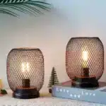 Battery table lamp with metal cage and warm LED glow on a wooden table