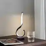 Modern desk lamp with adjustable arm and USB cable, glowing warmly on a wooden desk