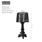 White ghost table lamp with transparent baroque design on a bedside table in a modern bedroom