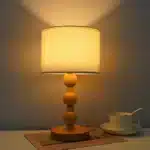 Vintage table lamp with fabric shade and solid wood base on bedside table