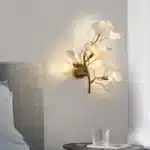 Luxury gold leaf sconce with modern ginkgo design illuminating a living room wall