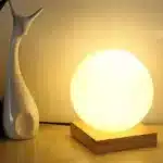 Modern table lamp with iron body and wood base illuminating a cozy bedroom