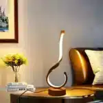 Modern desk lamp with adjustable arm and USB cable, glowing warmly on a wooden desk