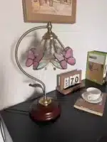 Vintage desk lamp with stained glass butterfly shade casting warm glow on bedside table