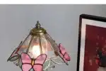Vintage desk lamp with stained glass butterfly shade casting warm glow on bedside table