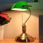 Antique bronze table lamp with green shade on bedside table
