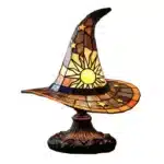 Witch hat lamp with stained glass pattern casting a warm glow on a bedside table