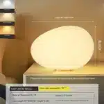 Warm night light pebble LED lamp glowing on a bedside table