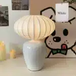 Vintage table lamp with retro ceramic base and silk shade on bedside table in cozy bedroom
