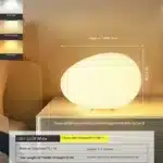 Warm night light pebble LED lamp glowing on a bedside table