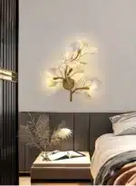 Luxury gold leaf sconce with modern ginkgo design illuminating a living room wall