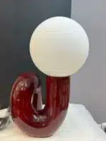 Modern glass table lamp with spherical shade on a wooden nightstand in a cozy bedroom