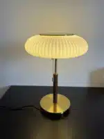 White glass table lamp with vintage design on a wooden desk in a cozy bedroom