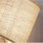 Vintage table lamp with hemp rope and iron base, emitting warm light on a bedside table
