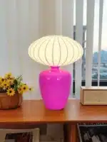 Vintage table lamp with retro ceramic base and silk shade on bedside table in cozy bedroom
