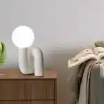 Modern glass table lamp with spherical shade on a wooden nightstand in a cozy bedroom