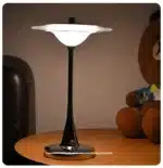 Goldoma rechargeable table lamp with flying saucer shape and warm glow on a bedside table