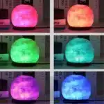 Salt lamp with color changing on wooden base glowing in warm light
