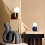 Modern glass table lamp with spherical shade on a wooden nightstand in a cozy bedroom