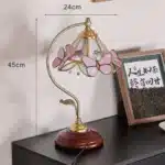 Vintage desk lamp with stained glass butterfly shade casting warm glow on bedside table