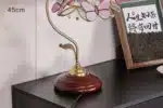 Vintage desk lamp with stained glass butterfly shade casting warm glow on bedside table