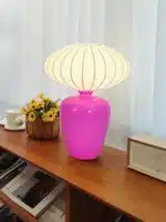 Vintage table lamp with retro ceramic base and silk shade on bedside table in cozy bedroom