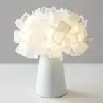 Modern table lamp with PVC flower design in a cozy bedroom setting