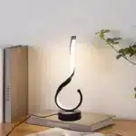 Modern desk lamp with adjustable arm and USB cable, glowing warmly on a wooden desk