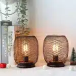 Battery table lamp with metal cage and warm LED glow on a wooden table