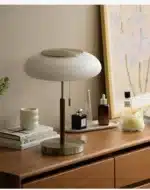 White glass table lamp with vintage design on a wooden desk in a cozy bedroom