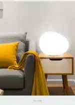 Warm night light pebble LED lamp glowing on a bedside table