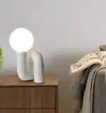 Modern glass table lamp with spherical shade on a wooden nightstand in a cozy bedroom