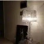 Modern acrylic table lamp glowing softly on a bedside table in a contemporary bedroom