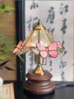 Vintage desk lamp with stained glass butterfly shade casting warm glow on bedside table