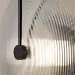 Modern wall lamp with minimalist Nordic design illuminating a cozy bedroom bedside