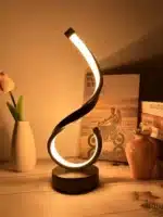 Modern desk lamp with adjustable arm and USB cable, glowing warmly on a wooden desk