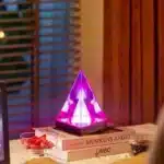 3D pyramid night light with RGB color modes on a bedside table