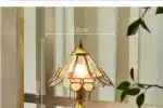 Vintage desk lamp with stained glass butterfly shade casting warm glow on bedside table