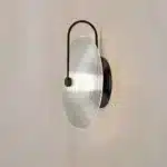 Modern wall lamp with minimalist Nordic design illuminating a cozy bedroom bedside