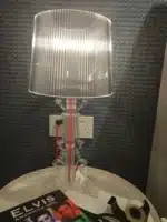 White ghost table lamp with transparent baroque design on a bedside table in a modern bedroom