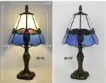 Tiffany table lamp with colorful stained glass shade casting warm glow on nightstand