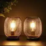 Battery table lamp with metal cage and warm LED glow on a wooden table