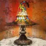 Witch hat lamp with stained glass pattern casting a warm glow on a bedside table