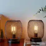 Battery table lamp with metal cage and warm LED glow on a wooden table