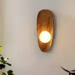 Vintage wall sconce with wooden backplate and clear glass shade, warm light