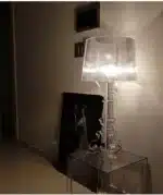 Modern acrylic table lamp glowing softly on a bedside table in a contemporary bedroom